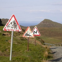 Fotografie von Thorsten Hülsberg mit verschiedenen verwitterten Warnschildern an einer Straße in den Highlands.